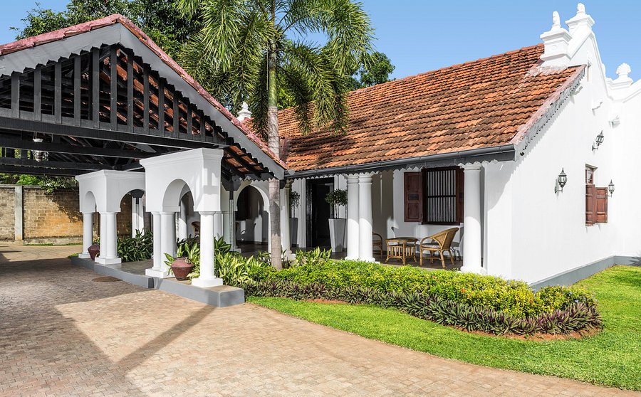 An outdoor daytime view of Fox Resorts Jaffna featuring traditional white colonial architecture, an orange-tiled pitched roof, an arched portico entryway, and a paved driveway in Sri Lanka