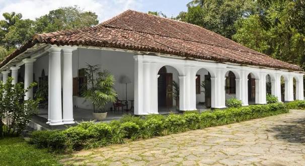An outdoor eye-level daytime view of The Kandy House featuring the historic white pillared veranda and tiled roof of the ancestral manor set in Kandy, Sri Lanka