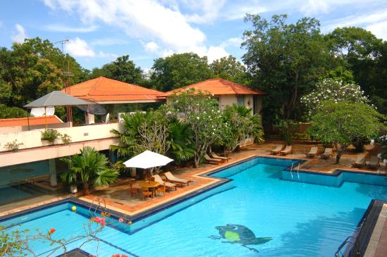 An outdoor daytime view of the Mandara Rosen hotel featuring a large swimming pool, lounge chairs, and resort buildings surrounded by trees in Kataragama, Sri Lanka