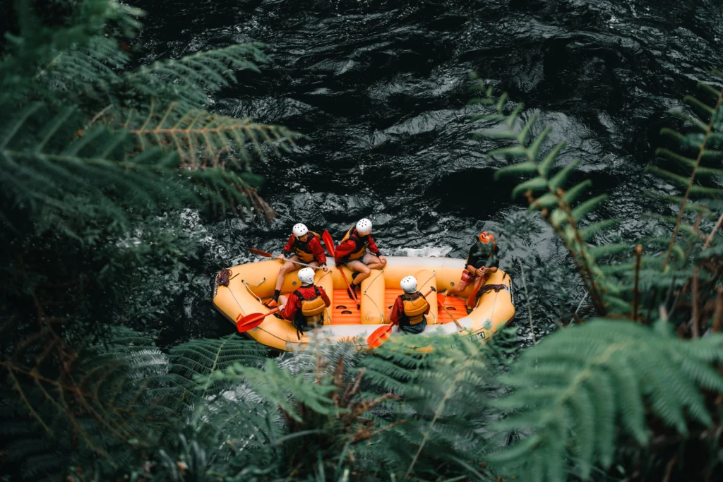 An outdoor daytime view in Sri Lanka featuring a yellow raft with people white-water rafting through a lush wilderness river surrounded by green ferns